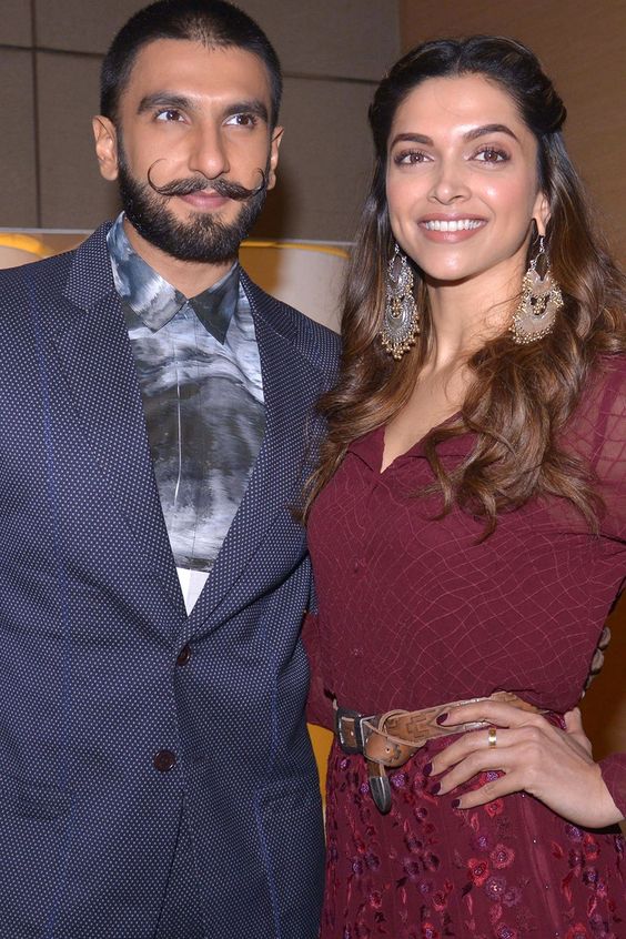 Deepika Padukone and Ranveer Singh smiling together with their newborn baby girl, marking a joyful moment as they embrace parenthood.