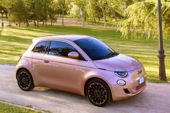 2024 Fiat 500 Electric parked on a city street with a modern skyline in the background, showcasing its retro-inspired design and electric features.