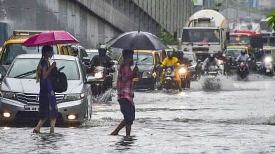 A flooded street in Mumbai with stranded commuters and vehicles.